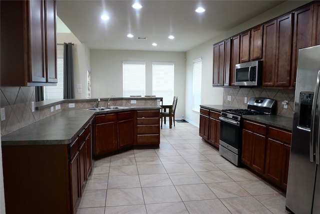 kitchen with backsplash, sink, light tile patterned flooring, dark brown cabinetry, and stainless steel appliances