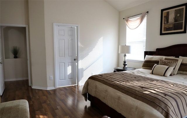 bedroom with dark wood-type flooring and lofted ceiling