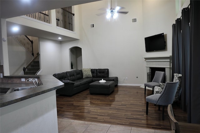 living room with tile patterned floors, ceiling fan, sink, and a towering ceiling