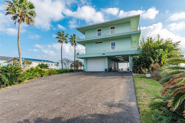 raised beach house featuring a balcony, a garage, and a carport