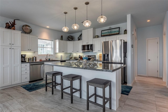 kitchen with stainless steel appliances, white cabinets, a kitchen island, hanging light fixtures, and a breakfast bar area