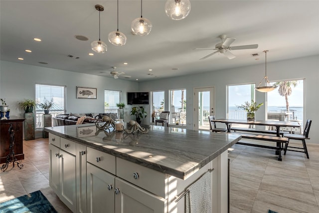 kitchen featuring ceiling fan, a center island, hanging light fixtures, and a wealth of natural light