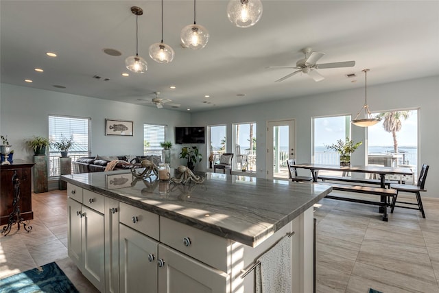 kitchen with recessed lighting, a kitchen island, a ceiling fan, decorative light fixtures, and open floor plan