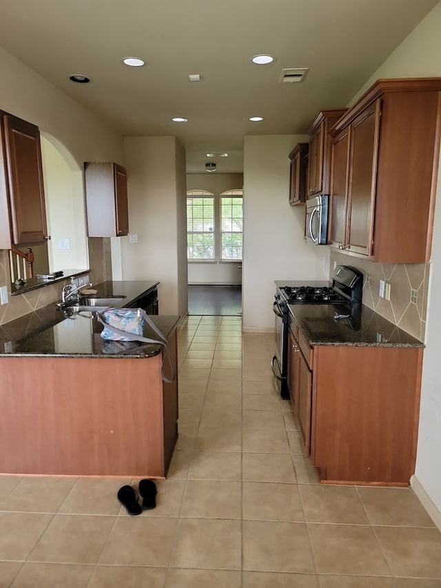 kitchen featuring dark stone countertops, light tile patterned floors, and appliances with stainless steel finishes