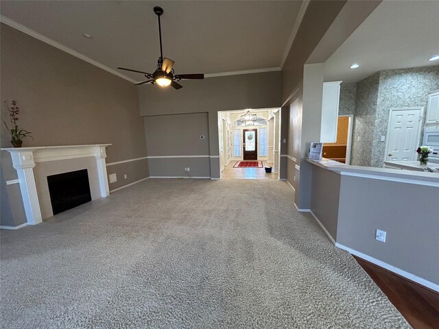 unfurnished living room with ceiling fan, ornamental molding, and carpet