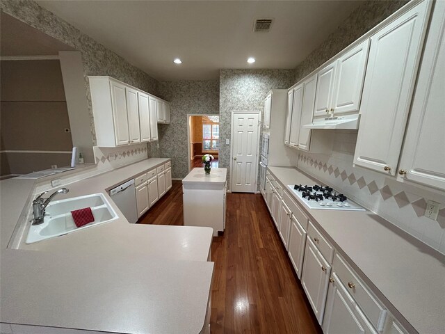 kitchen featuring sink, a center island, kitchen peninsula, white appliances, and white cabinets