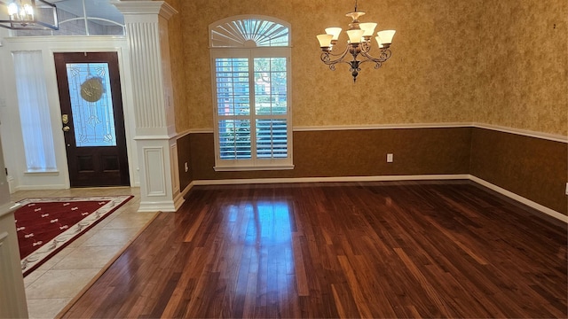 entrance foyer with an inviting chandelier, hardwood / wood-style flooring, and decorative columns