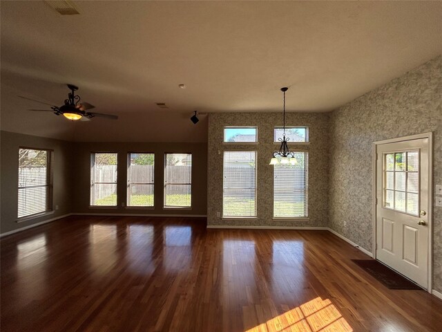 unfurnished dining area featuring dark wood-type flooring and ceiling fan with notable chandelier