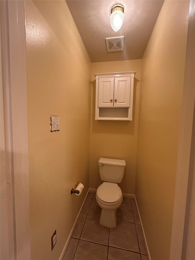 bathroom with toilet, tile patterned flooring, and a textured ceiling