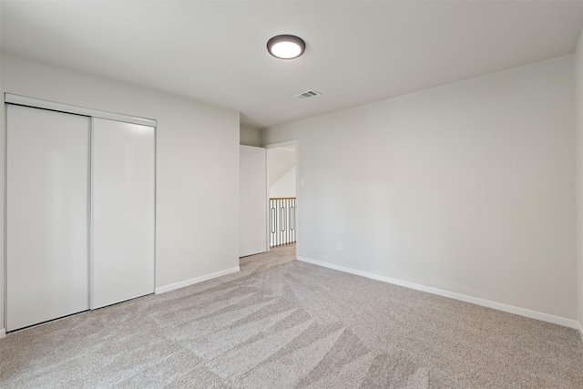 unfurnished bedroom with light colored carpet and a closet