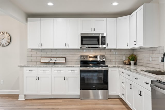 kitchen featuring sink, white cabinetry, backsplash, and appliances with stainless steel finishes