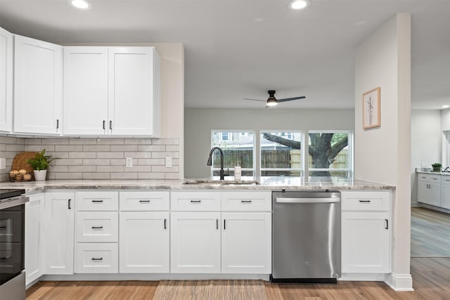 kitchen with white cabinetry, sink, light stone counters, and appliances with stainless steel finishes