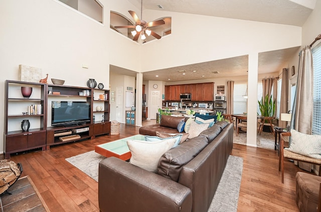 living room featuring ceiling fan, high vaulted ceiling, and wood-type flooring