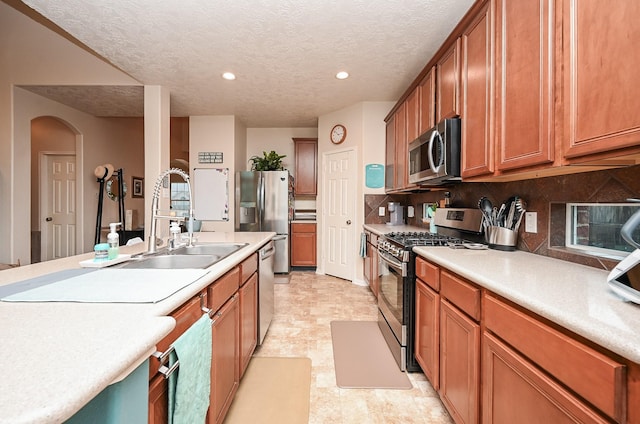 kitchen with appliances with stainless steel finishes, backsplash, a textured ceiling, and sink