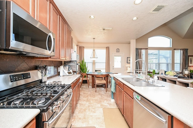 kitchen with pendant lighting, sink, vaulted ceiling, decorative backsplash, and stainless steel appliances