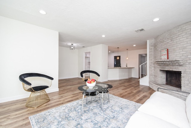 living room featuring hardwood / wood-style floors, a textured ceiling, and a brick fireplace