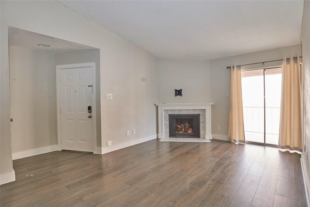 unfurnished living room with a fireplace, dark wood-type flooring, and a textured ceiling