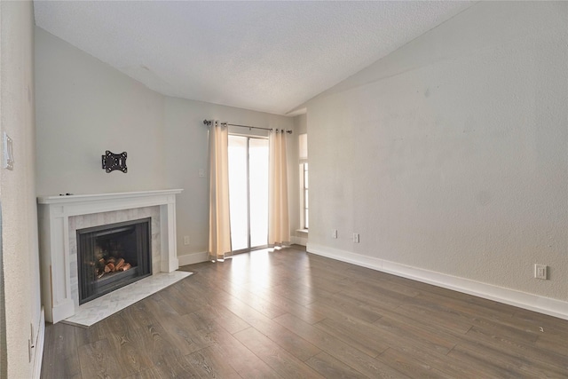 unfurnished living room featuring a textured ceiling, dark hardwood / wood-style floors, vaulted ceiling, and a tiled fireplace