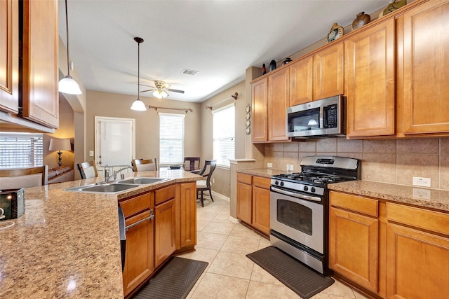 kitchen featuring sink, hanging light fixtures, light tile patterned flooring, light stone counters, and stainless steel appliances