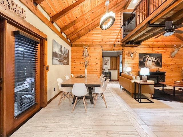 dining space with high vaulted ceiling, wooden walls, ceiling fan, light hardwood / wood-style floors, and beam ceiling