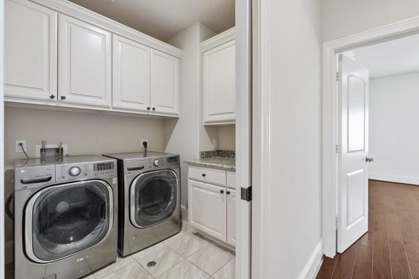 clothes washing area featuring cabinets, light wood-type flooring, and washer and clothes dryer