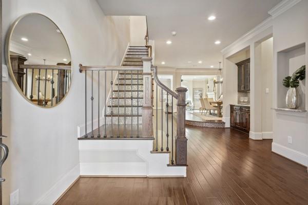 stairway with wood-type flooring and crown molding