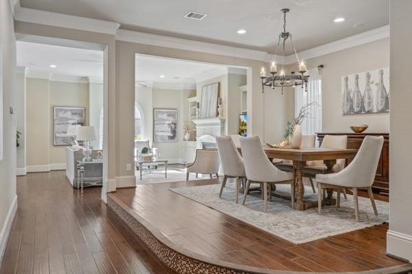 dining area featuring dark hardwood / wood-style flooring, an inviting chandelier, and ornamental molding