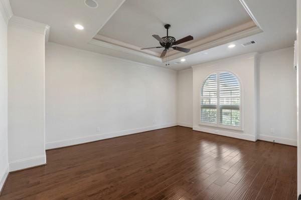 spare room featuring dark hardwood / wood-style flooring, a tray ceiling, ceiling fan, and crown molding