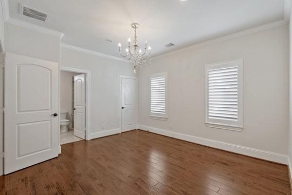 empty room featuring dark hardwood / wood-style flooring, ornamental molding, and an inviting chandelier