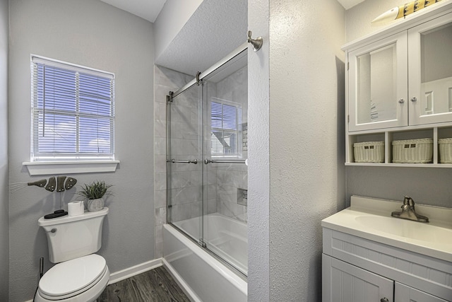 full bathroom featuring toilet, vanity, enclosed tub / shower combo, and hardwood / wood-style flooring