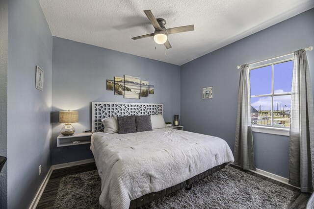 bedroom with ceiling fan, dark hardwood / wood-style floors, and a textured ceiling