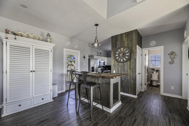 kitchen featuring a textured ceiling, stainless steel appliances, a wealth of natural light, and a breakfast bar area