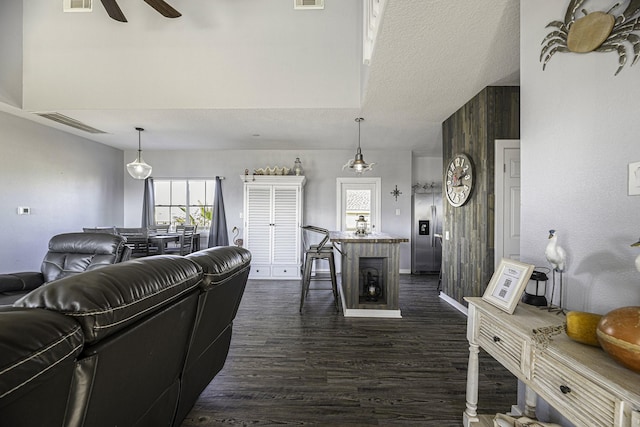 living room with ceiling fan, dark hardwood / wood-style floors, and a textured ceiling