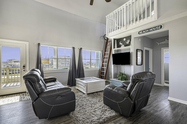 living room with a towering ceiling, dark hardwood / wood-style flooring, built in features, and ceiling fan