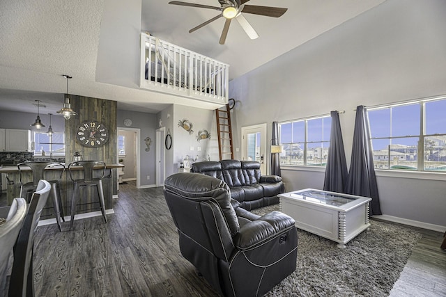 living room featuring ceiling fan, dark hardwood / wood-style flooring, a towering ceiling, and a textured ceiling