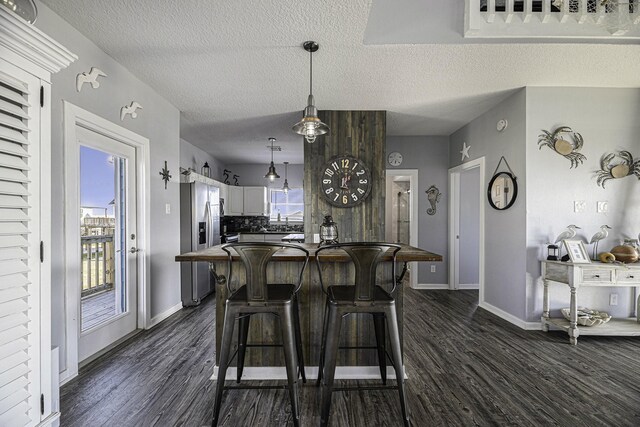 kitchen featuring white cabinets, pendant lighting, a textured ceiling, and dark hardwood / wood-style flooring