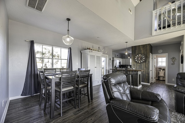 dining space with dark hardwood / wood-style floors, a textured ceiling, and high vaulted ceiling