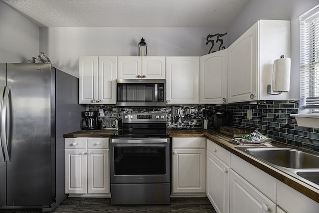 kitchen with a wealth of natural light, white cabinets, stainless steel appliances, and a textured ceiling