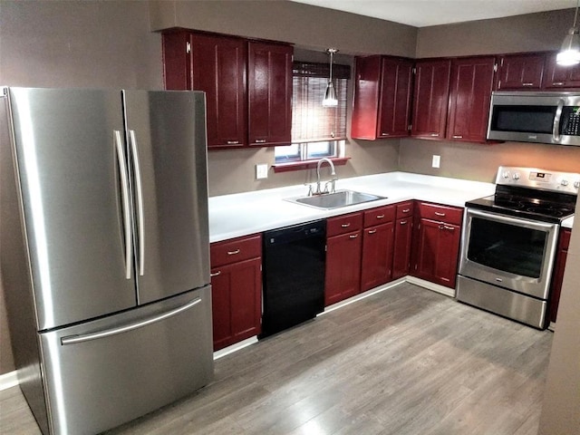 kitchen featuring sink, light hardwood / wood-style flooring, pendant lighting, and appliances with stainless steel finishes