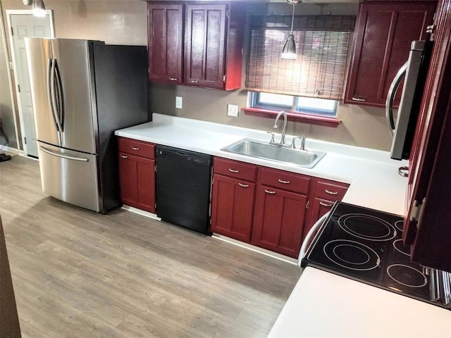 kitchen featuring stainless steel fridge, sink, decorative light fixtures, dishwasher, and light hardwood / wood-style floors