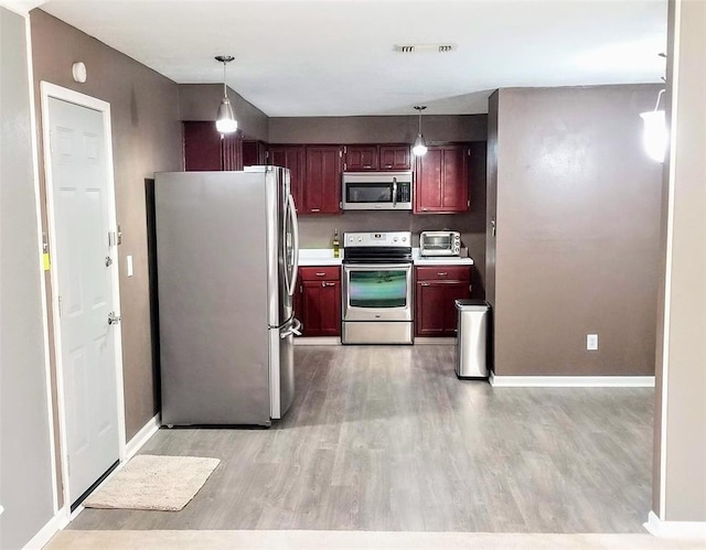 kitchen featuring pendant lighting, light wood-type flooring, and appliances with stainless steel finishes