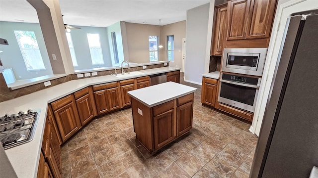 kitchen with hanging light fixtures, sink, ceiling fan, appliances with stainless steel finishes, and kitchen peninsula