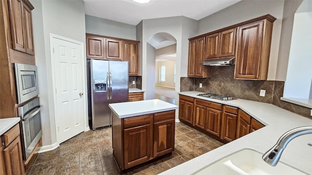 kitchen with ventilation hood, a center island, stainless steel appliances, and tasteful backsplash