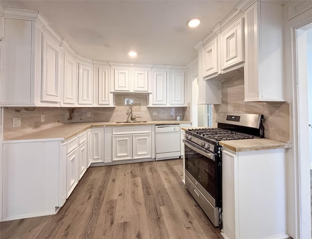 kitchen featuring dishwasher, stainless steel gas range oven, white cabinets, sink, and light hardwood / wood-style flooring