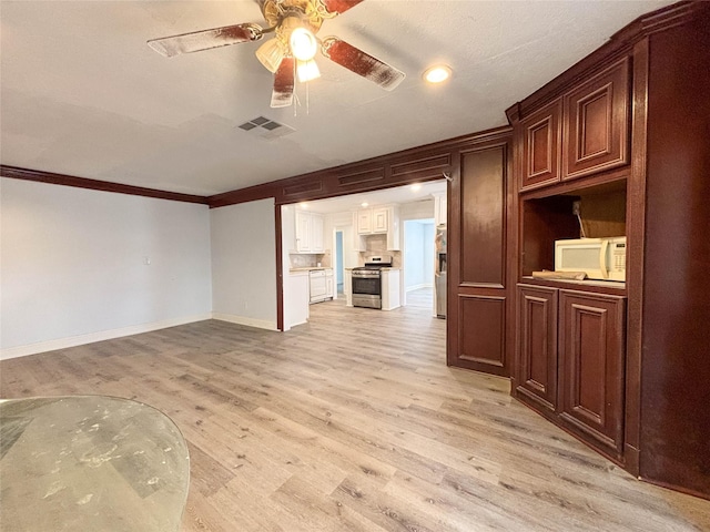 spare room featuring light wood-type flooring, visible vents, ornamental molding, a ceiling fan, and baseboards