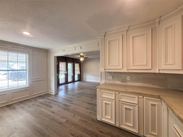 kitchen with a decorative wall, crown molding, light countertops, and wood finished floors