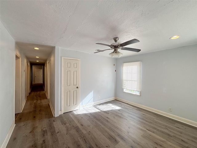 unfurnished room with ceiling fan, dark hardwood / wood-style flooring, and a textured ceiling