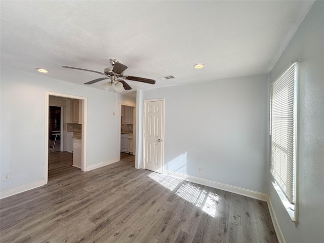 empty room with ceiling fan, a healthy amount of sunlight, and wood-type flooring