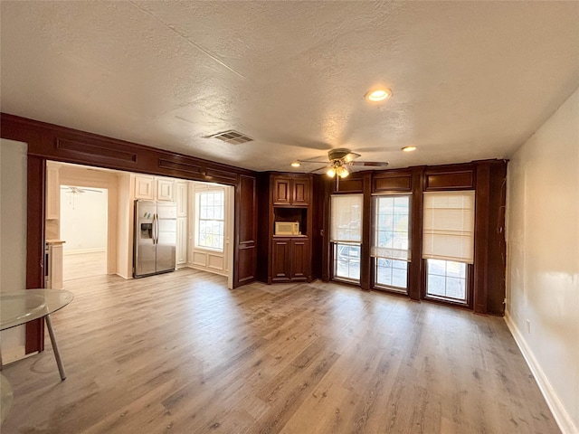 unfurnished living room with ceiling fan, light hardwood / wood-style flooring, and a textured ceiling