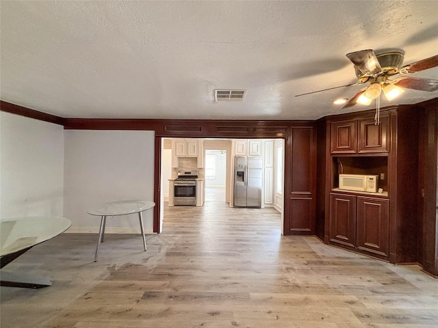 kitchen with a textured ceiling, stainless steel appliances, light wood-style floors, and a ceiling fan